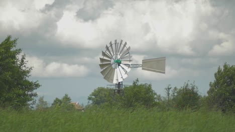 Dutch-Old-American-Windmill-near-the-water-ans-reed,-a-small-Dolly-shot-in-slowmotion-turning-in-the-wind