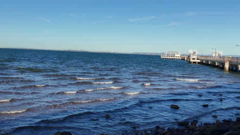 Slow-Panning-Shot-of-Woody-Point-Jetty-with-ocean-waves-on-a-cold-sunny-morning
