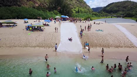 Drone-Shot-following-some-kids-trying-to-slide-down-a-man-made-slip-n-slide-at-Waimea-Bay