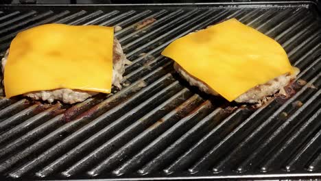 Zwei-Hausgemachte-Cheeseburger-Kochen-Auf-Einem-Schwarzen-Grill