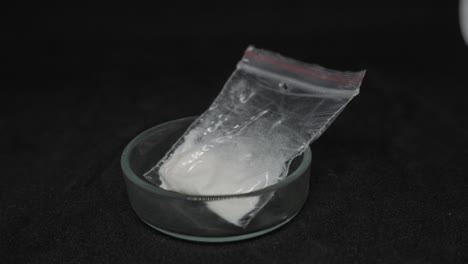 Cocaine-toxic-packet-being-picked-from-a-ashtray-with-forceps,-closeup
