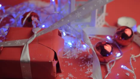 Ein-Silbernes-Schleifenband-An-Ein-Weihnachtsgeschenk-Mit-Rotem-Papier-Mit-Rotem-Hintergrund-Und-Kugeln-Binden