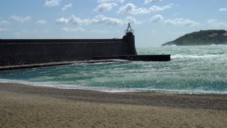 Strong-waves-break-around-the-harbour-wall-of-Collioure-while-heavy-winds-whip-up-the-water-which-sprays-on-the-wall