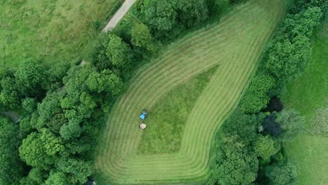 Top-down-aerial-of-a-triangular-grass-field-being-cut-in-a-visually-pleasing-manner