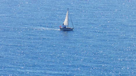 Yacht-sailing-on-wide-blue-sea-with-sparkling-waves,-Mediterranean