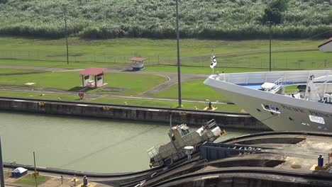Panama-canal-barge-truck-pulling-cruise-liner-ship-along-narrow-waterway-channel