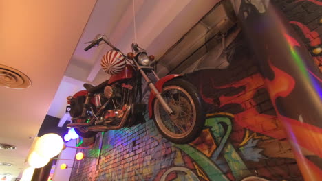 Editorial,-view-of-inside-restaurant-,-beautiful-modern-decor-and-design,-motorcycle-hanged-to-ceiling,-colorful-graffiti-wall,-and-people-eating-in-restaurant