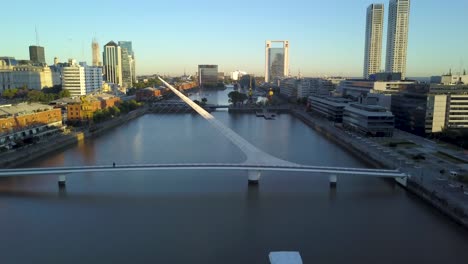 Aerial-shot-of-Woman’s-Bridge-and-Puerto-Madero-docks-at-sunset,-Buenos-Aires