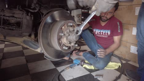 Mechaniker,-Die-An-Der-Achse-Eines-Autos-Arbeiten-Und-Versuchen,-Sie-Zu-Reparieren