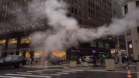 Steam-rising-from-an-orange-steam-pipe-while-cars-passing-by-and-people-walking-at-the-intersection-of-West-37th-Street-and-Broadway-in-120-fps-slow-motion---Manhattan,-New-York-City