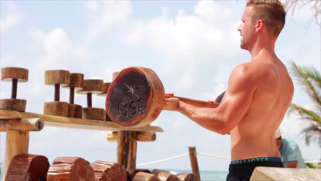 medium-shot,-man-blonde-doing-exercise-on-the-beach-with-wood-made-equipment