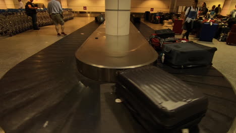 Flughafen-Gepäckkarussell,-Förderband,-Koffer--Und-Gepäckbewegung,-Passagiere,-Die-Nach-Der-Flugankunft-Im-Flughafenterminal-Auf-Ihr-Gepäck-Warten-Und-Suchen,-Taschen-Auf-Dem-Band,-Gepäck-Abholen