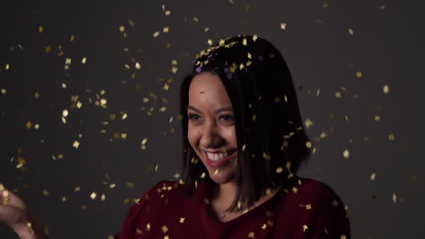 Young-woman-smiles-sweetly-while-getting-pelted-with-golden-confetti---Slow-motion