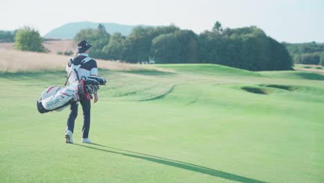 Golfer-on-golf-course-carrying-bag-with-clubs,-camera-orbits