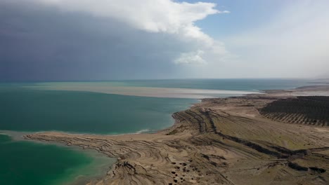 aerial-shot-over-Dead-Sea-desert-beach,-amazing-half-cloudy-sky,-Israel