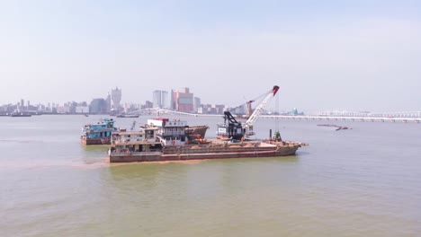 Drone-orbit-shot-of-grab-dredge-and-hopper-barges-with-reveal-of-Macau-city-skyline-in-background