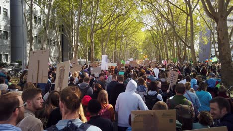 Eine-Riesige-Menge-Studenten,-Teenager-Und-Andere-Demonstranten-Marschieren-Einen-Boulevard-Mit-Bäumen-Entlang,-Um-Politische-Maßnahmen-Gegen-Die-Globale-Erwärmung-Zu-Fordern