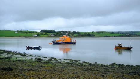 RNLI-lifeboat-moored-with-other-small-boats-during-low-tide-and-calm-ocean-in-the-county-Cork,-Ireland