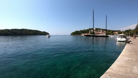 Boat-approaches-Cavtat-town,-Croatia-with-people-on-board-on-a-sunny-summer-day