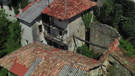 Low-drone-flight-over-crumbling-houses-and-structures-in-an-abandoned-village,-Slovenia