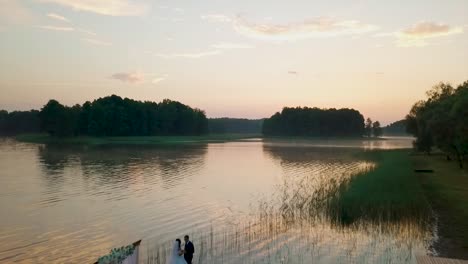 Aerial-view-of-a-couple-getting-married-near-a-lake-during-the-sunset