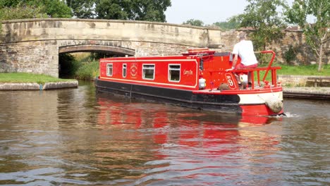 British-staycation-red-canal-boat-steering-turning-navigating-Welsh-bridge-waterway