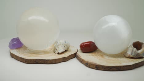 Zwei-Runde-Kristallkugeln-Auf-Einem-Holz-Mit-Kleinen-Edelsteinen-Und-Muscheln-Dazwischen---Nahaufnahme