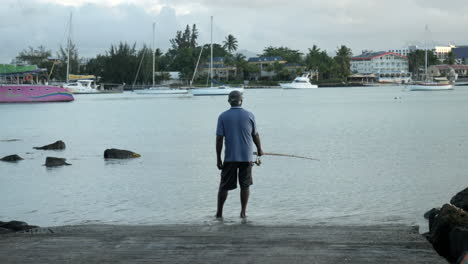 Toma-Trasera-De-Un-Pescador-Mauriciano-Pescando-En-La-Orilla-Del-Puerto,-Estático