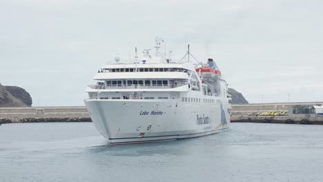 Large-white-passenger-ship-maneuvers-in-Porto-Santo-port-waters-by-cement-pier-in-harbor,-Portugal,-static-portrait