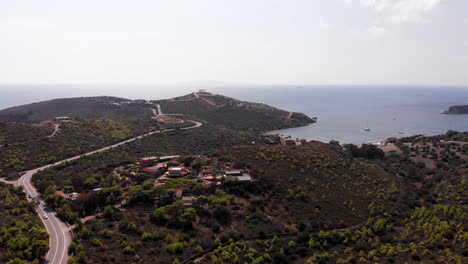 Cape-Sounion-with-Greek-temple-of-Poseidon-in-distance,-panning-aerial