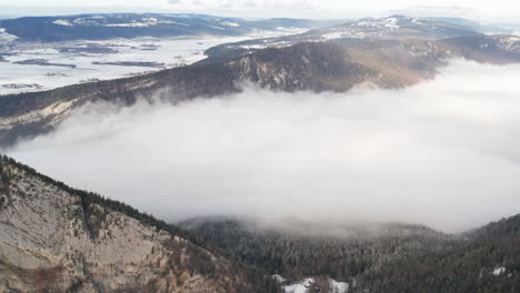 Aerial-of-low-hanging-clouds-in-snow-covered-mountain-pass