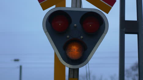 A-yellow-blinking-light-at-a-train-track-intersection-signaling-caution---Close-up