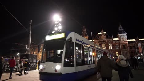 -Amsterdam-dam-square-and-central-station-during-New-Year's-Eve-with-people-and-Tram-passing-by