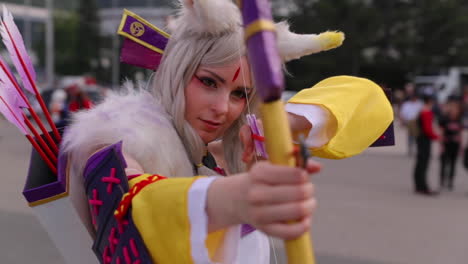 A-woman-dressed-in-archery-in-comic-white,-purple-jersey-aiming-with-a-bow-and-arrow-in-front-of-her-during-anime-comics-and-manga-lovers-AnimeFest-Brno-expo-camera-in-120fps