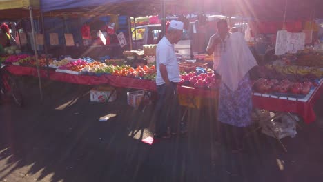Vista-De-La-Gente-En-El-Mercado-De-Comida-Callejera-Comprando-Frutas-En-El-Puesto-De-Vendedor-Por-La-Noche
