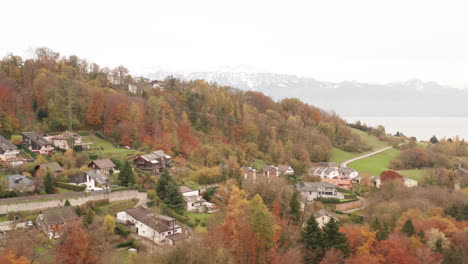 Aerial-of-small-rural-town-in-woodland-area-and-mountains-in-the-background