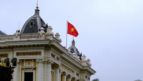 Hanoi-Opera-House-rooftop-with-the-Vietnamese-Flag-waving,-located-on-the-Square-of-August-Revolution,-Locked-close-up-shot