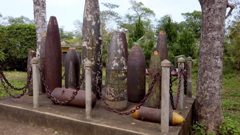 Captured-ordnance-bombs-and-artillery-shells-from-the-Vietnam-War-at-a-monument-near-the-war-tunnels,-Handheld-walking-shot