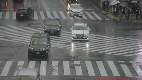 Autos-Und-Taxis-Fahren-Bei-Regnerischem-Wetter-Auf-Der-Nassen-Straße-Am-Shibuya-Kreuz-In-Tokio-–-Hauptverkehrszeit-–-Nahaufnahme,-Teleaufnahme