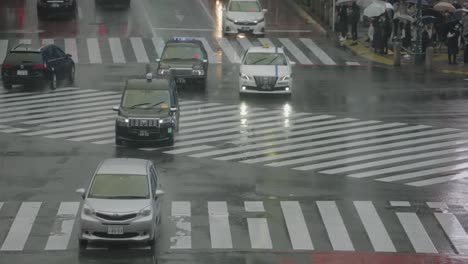 Verkehrsszene-Am-Shibuya-Kreuzung-In-Tokio,-Japan-An-Einem-Regnerischen-Tag-–-Taxis-Fahren-In-Zeitlupe-–-Teleaufnahme