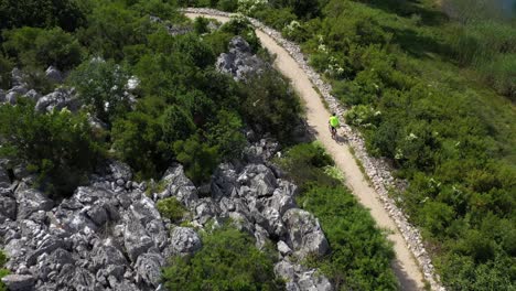 Biker-Speeding-On-Rocky-Mountain-Trail-Near-Bacina-Lake-In-Croatia---aerial