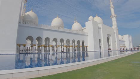 Visitantes-Por-La-Entrada-A-La-Gran-Mezquita-Sheikh-Zayed,-Pasillo-Con-Piscina-De-Reflexión