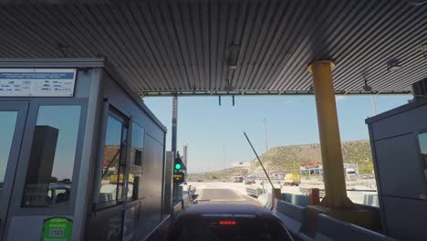 Footage-from-helmet-camera,-motorcycle-rider-pov,-passing-a-toll-station-on-Greek-national-highway,-summer-of-2020