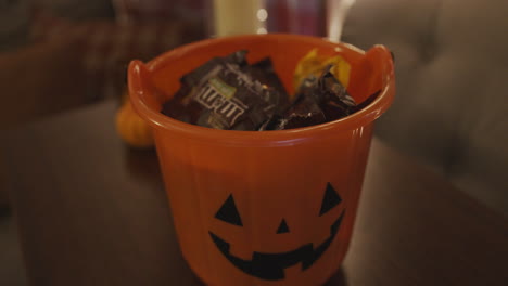 Zeitlupen-Nahaufnahme-Von-Süßigkeiten,-Die-In-Einen-Halloween-Kürbiseimer-Fallen