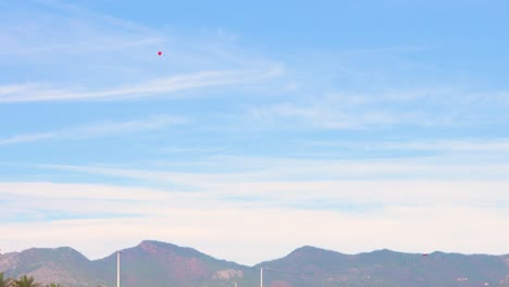 Paratrooper-from-afar-with-the-castellon-mountains-in-the-background,-landing-in-benicassim