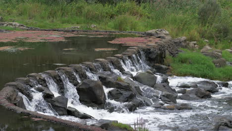 Birds-Fly-Over-River-Water-Flowing-Through-Stone-Weir,-SLOW-MOTION