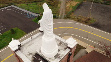 An-aerial-view-of-a-statue-of-the-Virgin-Mary-on-top-of-a-Catholic-Church-in-upstate,-NY