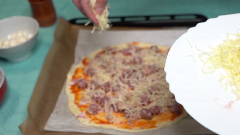 Selective-focus-plate-with-cheese-and-woman-distributing-cheese-on-pizza-in-the-background