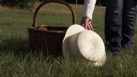 Woman-putting-straw-hat-and-woven-basket-in-a-field