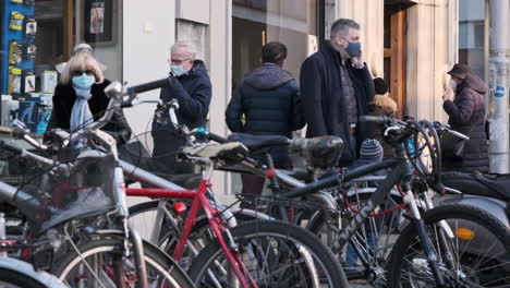 Bicycle-Parking-In-City-Center-With-People-Walking-Outside-The-Shops-Wearing-A-Medical-Mask-During-Covid-19-Pandemic-in-Monza,-Northern-Italy